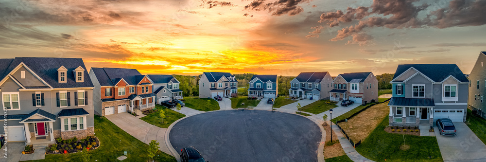 Cul de sac classic dead end street surrounded by luxury two story single family homes in new residential East Coast USA real estate suburban neighborhood dramatic colorful yellow orange sunset sky